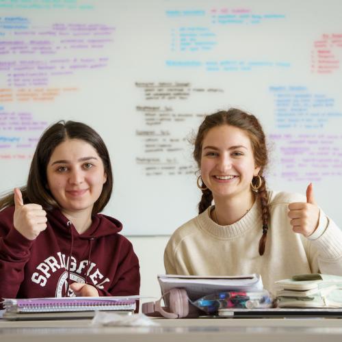 2 students giving a thumbs up in a classroom